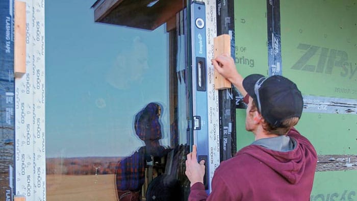 - Installation of sliding glass door with green sheathing and flashing tape. - Option 3: Person adjusting door frame for proper fit on new build. Would you like me to make these more SEO-friendly by including terms like “energy-efficient doors” or “professional installation” for social media use?