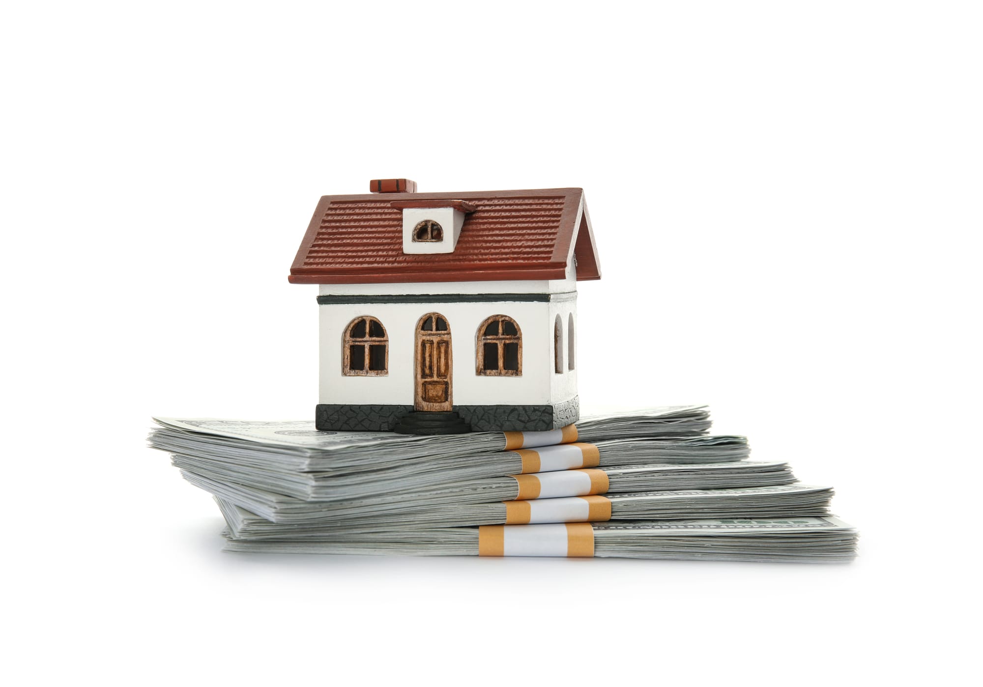 A small model house placed on top of neatly stacked bundles of cash, representing home value, equity, or a fast cash home sale.