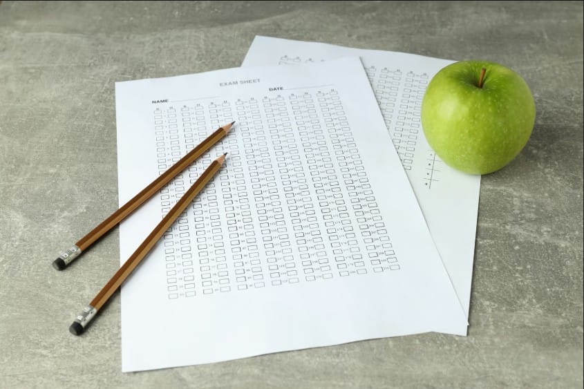 Standardized testing concept featuring an exam bubble sheet, pencils, and a green apple, representing test preparation, school exams, and academic performance.