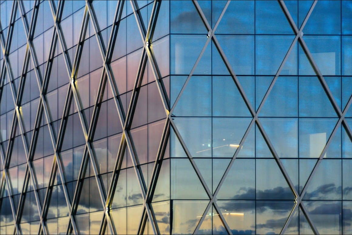 Contemporary architectural glass facade featuring a diagrid structure with sunset reflections.
