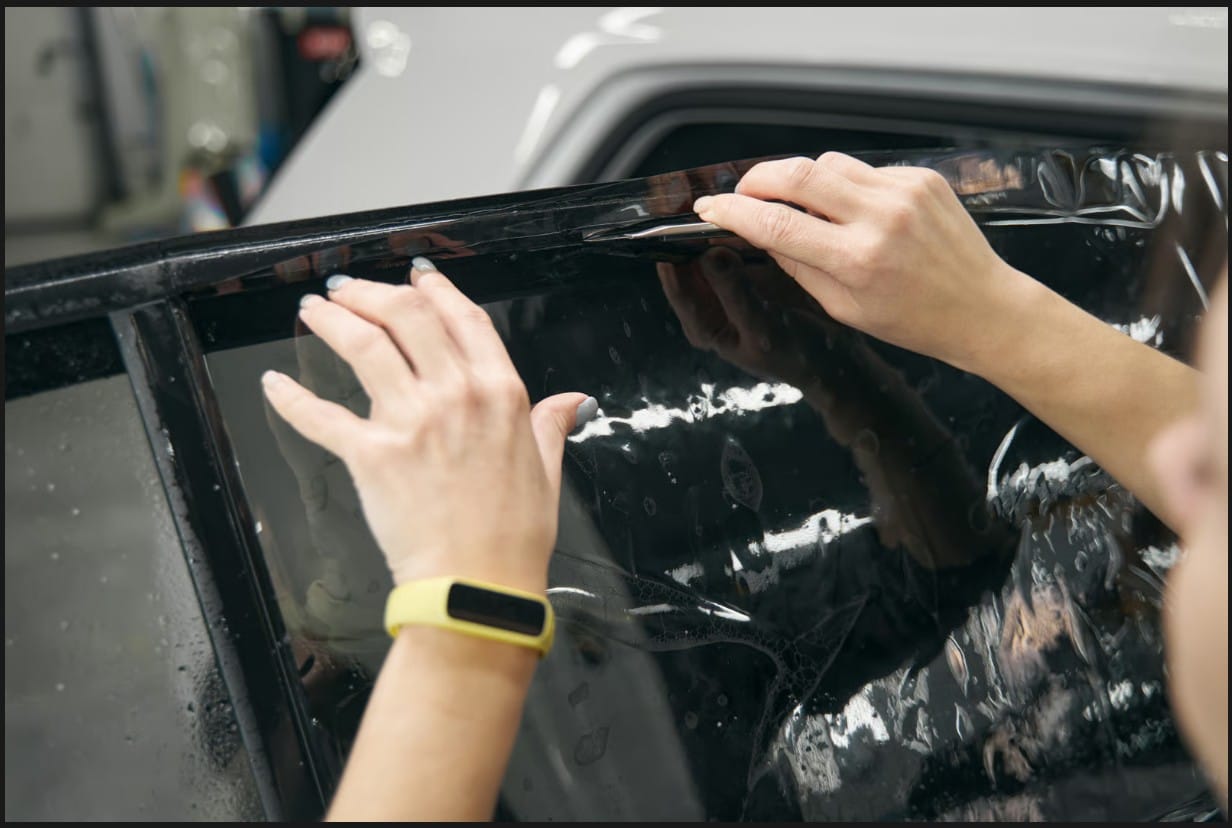Precision installation of UV protection window tint film on a vehicle for sun and heat rejection.