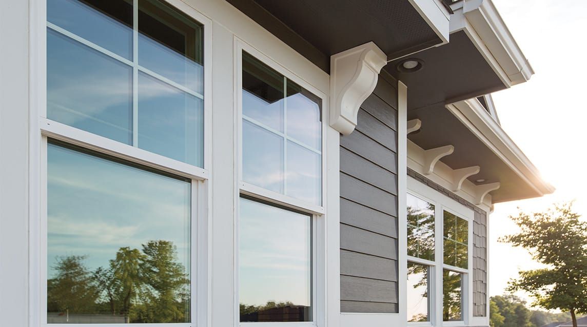 Modern home exterior with large white-trimmed windows and dark gray siding.