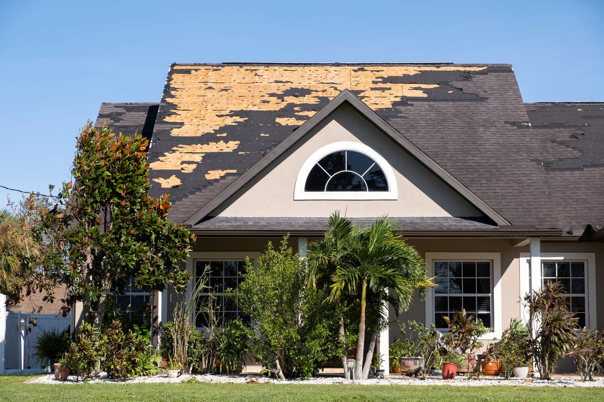 Sacramento-area home with severe roof damage and missing asphalt shingles, exposing the wood decking underneath.