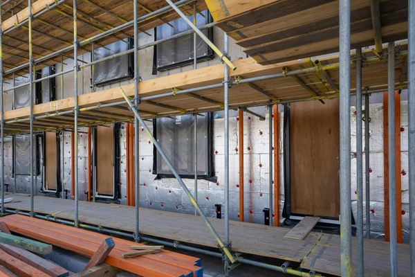 A building exterior surrounded by scaffolding during insulation work.