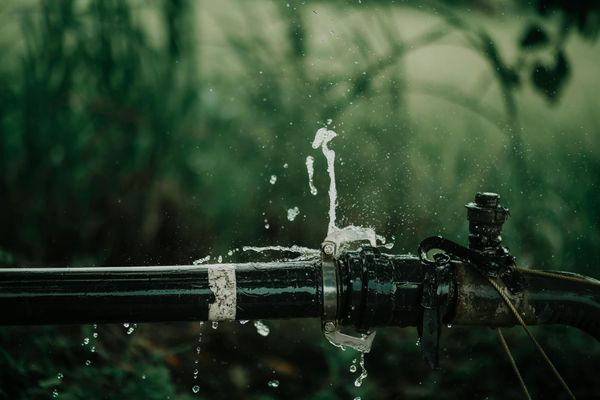 Leaking outdoor metal pipe spraying water from a joint connection.