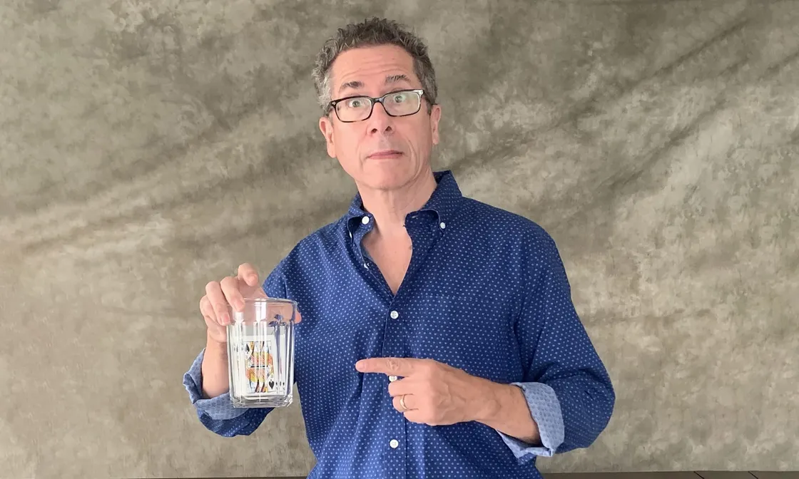 David Regal holding a glass cup with the Queen of Spades