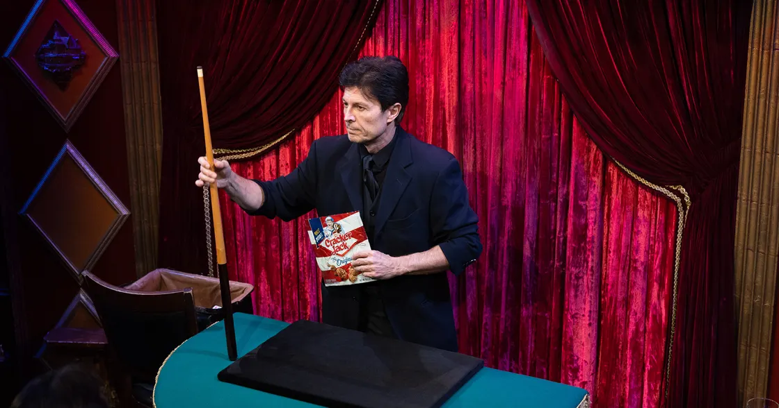 Ivan Amodei performing at The Magic Castle, Ivan holds the tools of his trade: a pool cue and a bag of Cracker Jacks