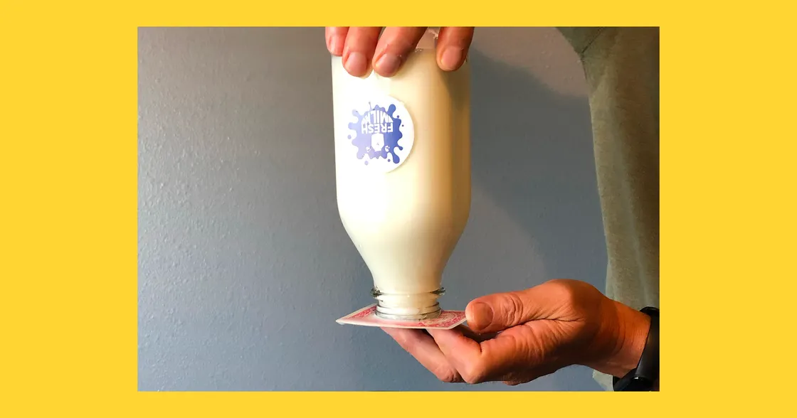 Person holding milk bottle upside down on playing card