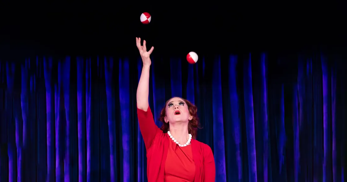 Woman juggling in front of blue curtain