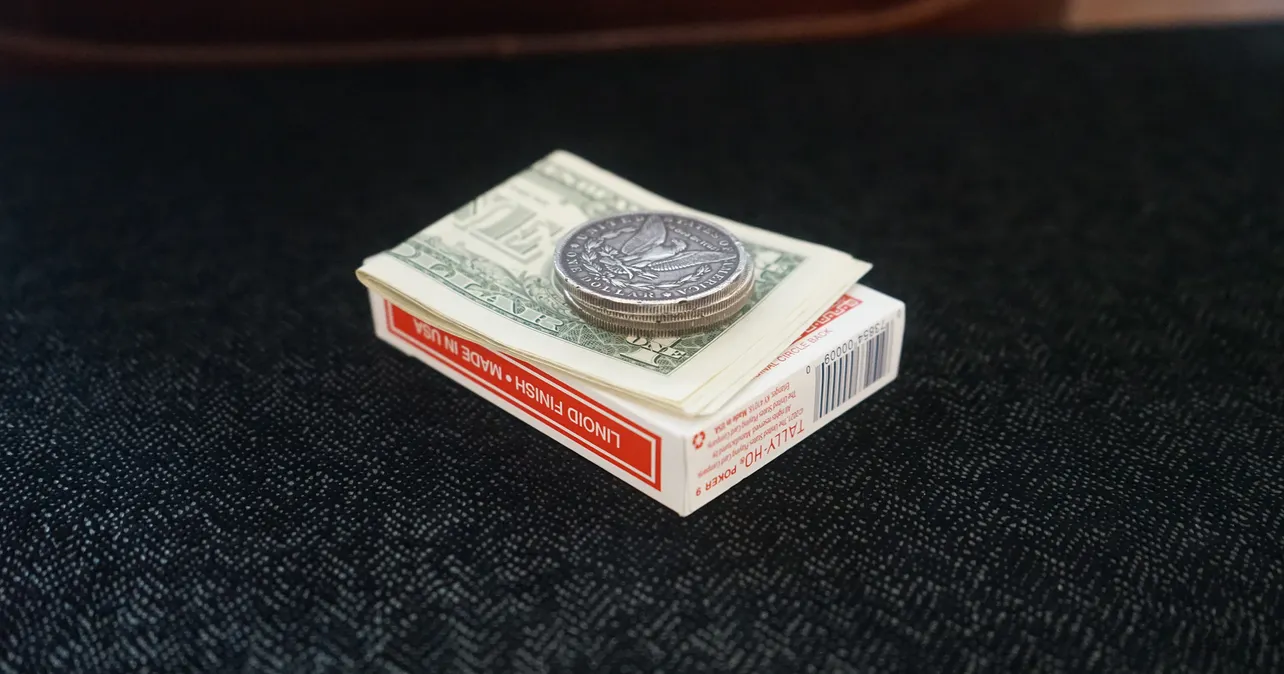 A stack of quarters on dollars and card box