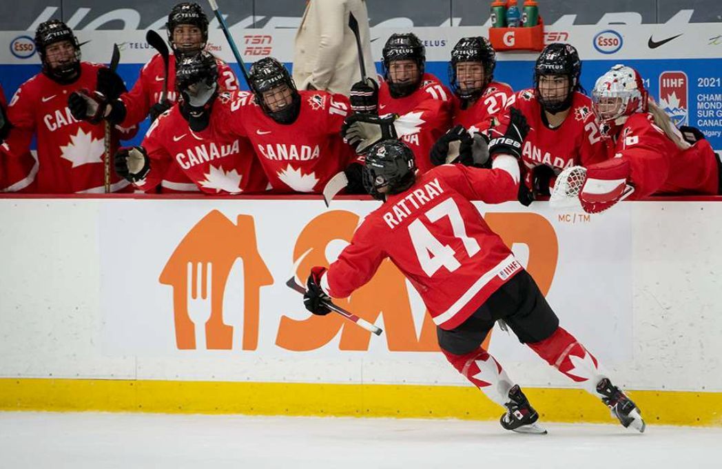 Forward Jamie Lee Rattray skates past the Team Canada bench celebrating a goal.