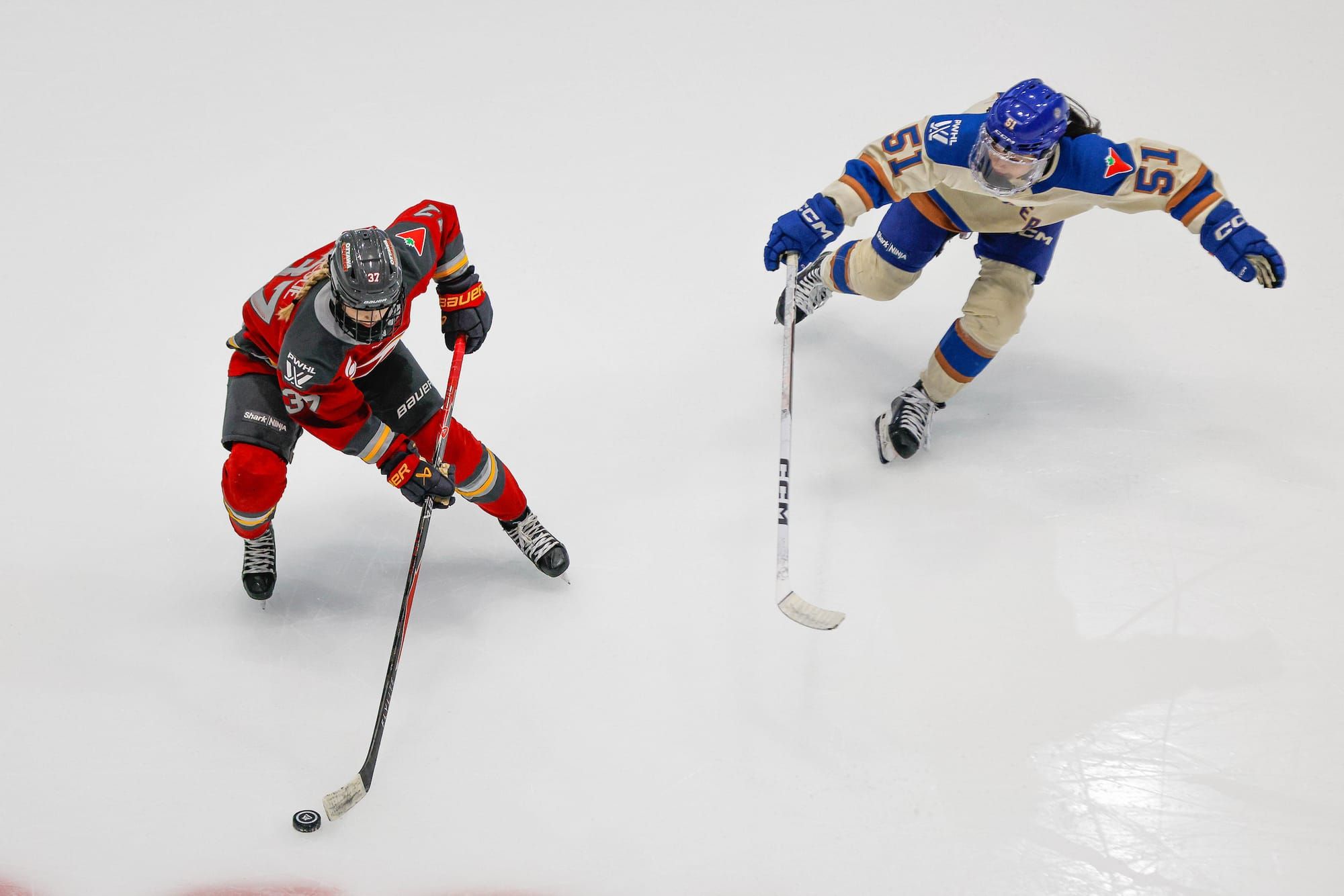 Ottawa Charge forward Rebecca Leslie, seen from above, protects the puck against Vancouver Goldeneyes forward Anna Segedi.