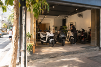 Illustrative unbranded electric-motorcycle dealer storefront on a tropical city street
