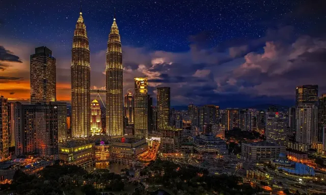 Kuala Lumpur skyline at dusk, with the Petronas Towers and city buildings illuminated.