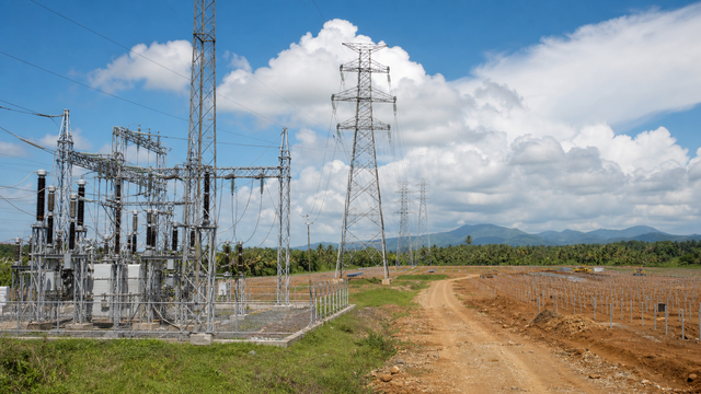A Mindanao power substation and transmission corridor with solar construction frames in a tropical landscape.