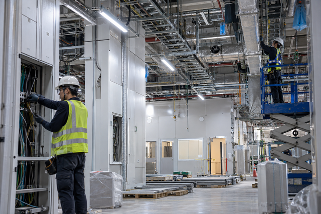 Illustrative semiconductor facility fit-out with technicians installing infrastructure, not an actual iCents customer site