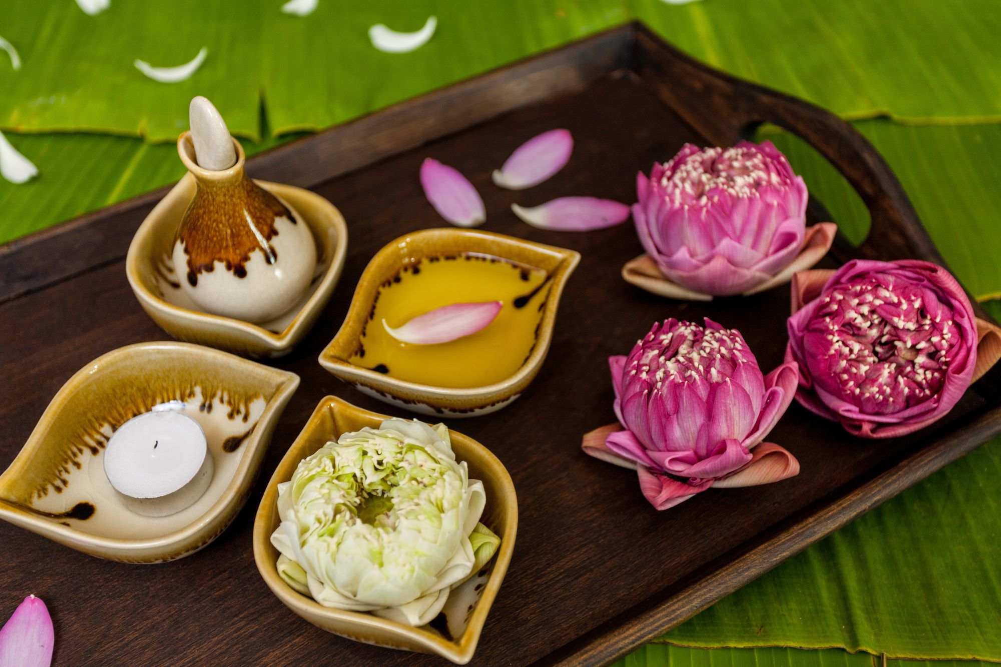 Tray with essential oil for massage, lots blossoms, and a candle