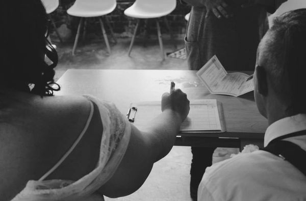 Black-and-white photo of two women signing their marriage certificate, symbolizing reconciliation and lasting love after ghosting.