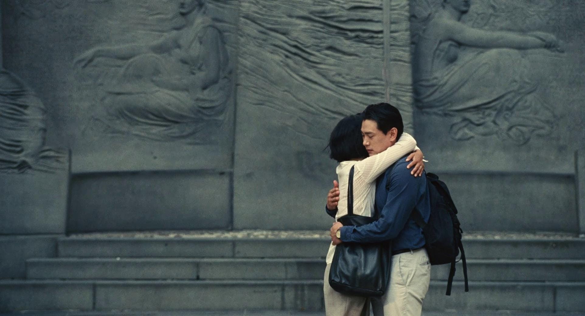 A man and a woman hug in front of steps.