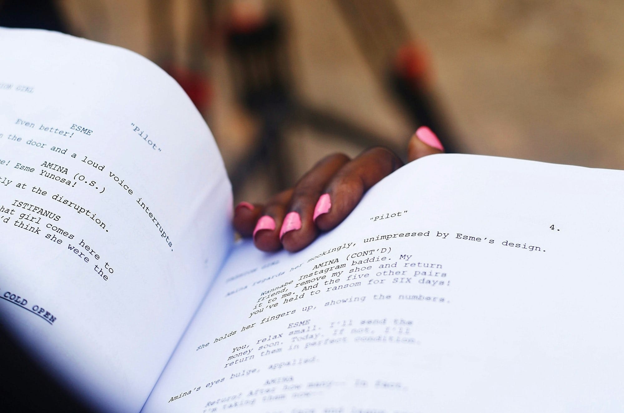 Hand resting on open script with camera in background