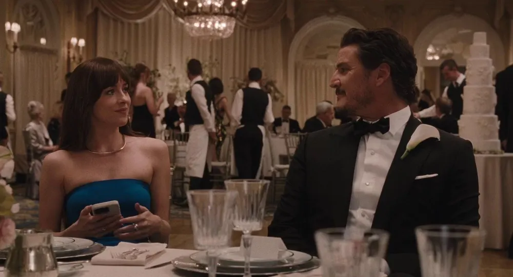 A man and woman sit together at a table during a wedding.