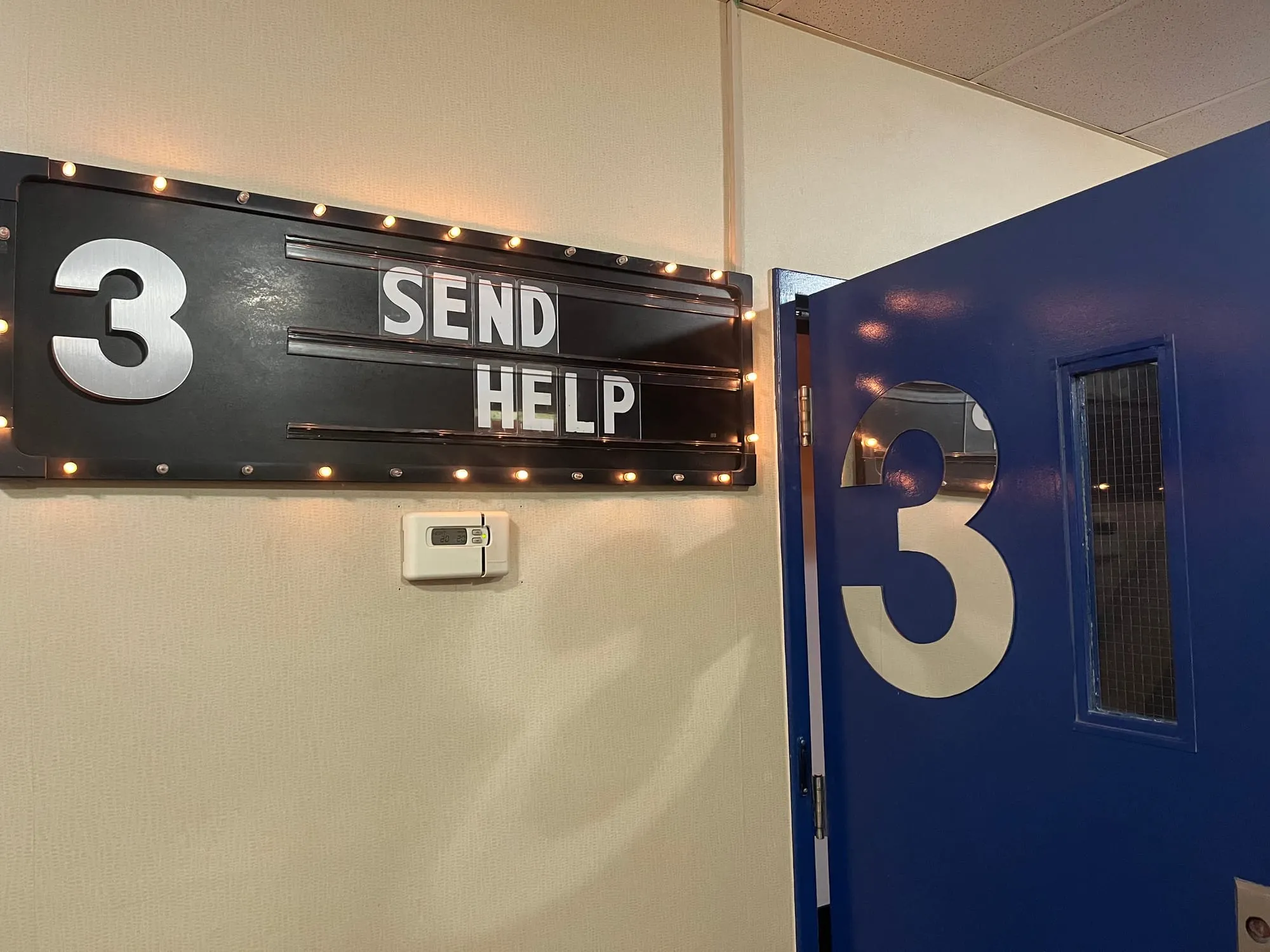 A sign reads "Send Help" outside a theatre door labeled 3.