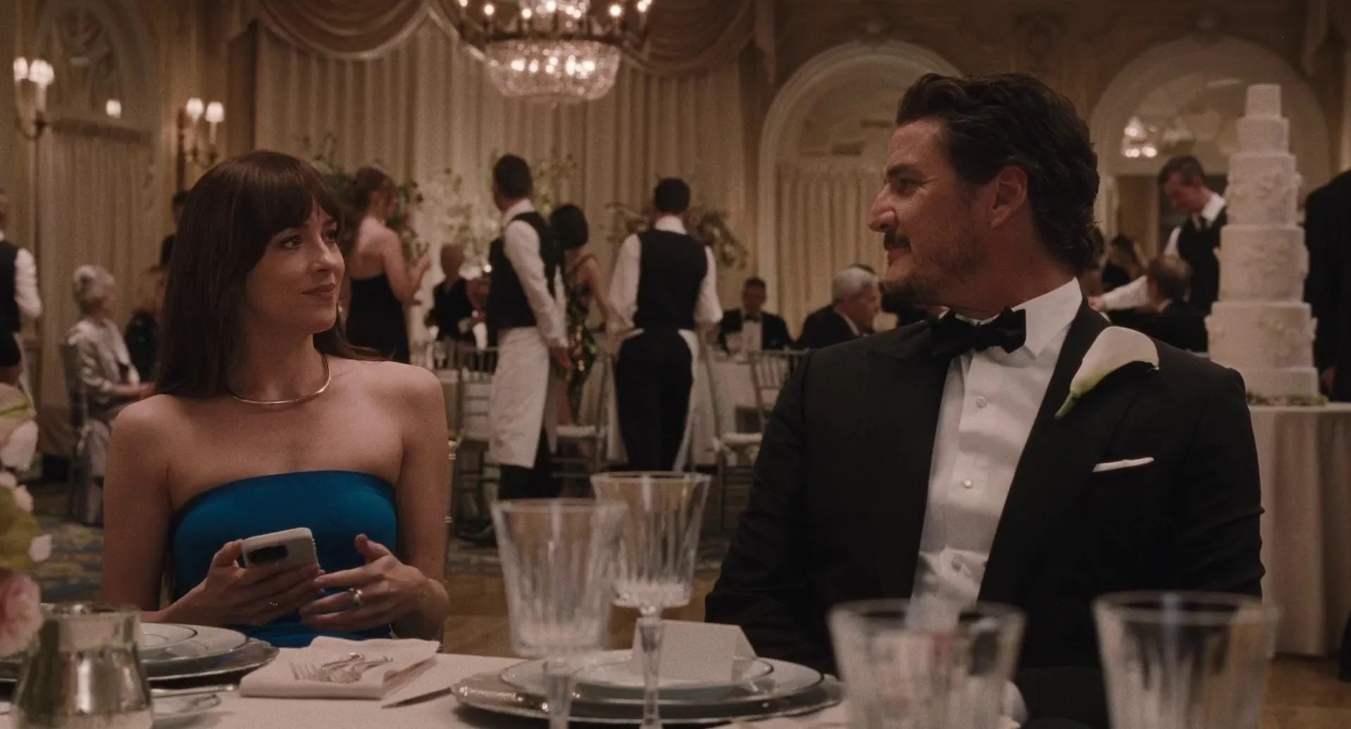 A man and woman sit together at a table during a wedding.