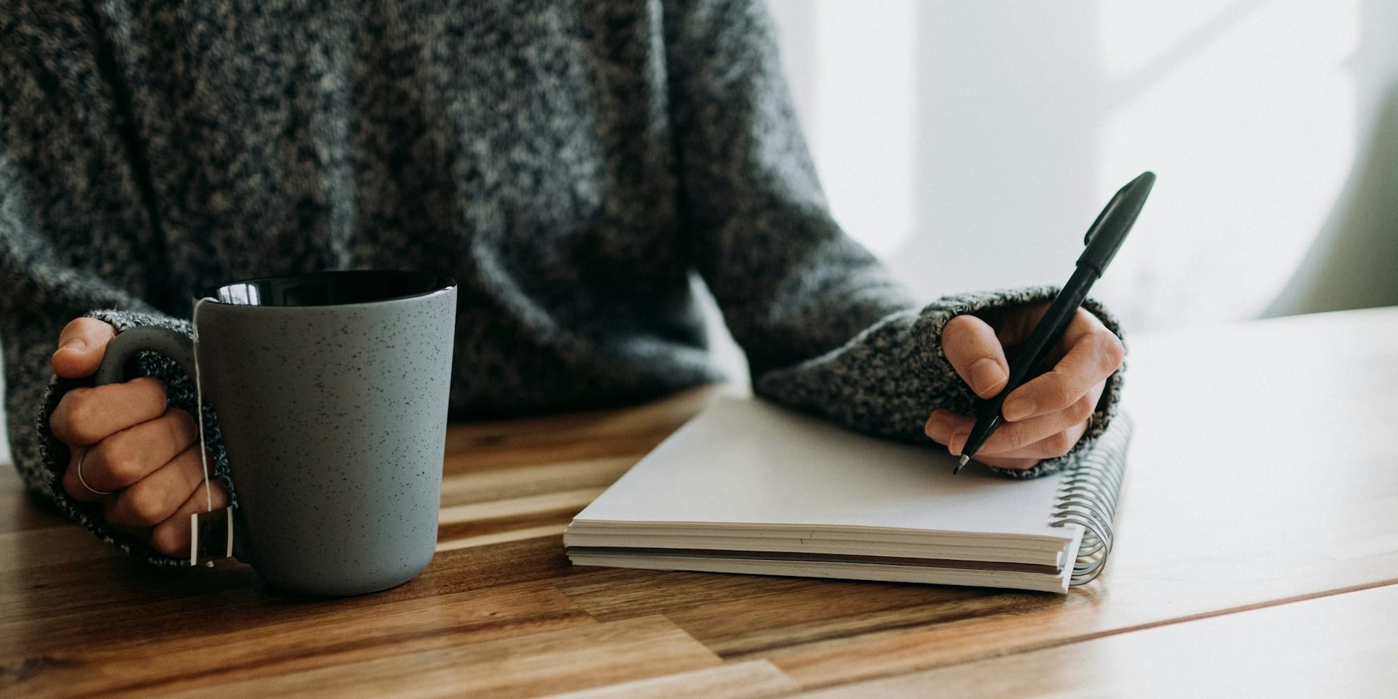 a person holding a pen and writing on a notebook