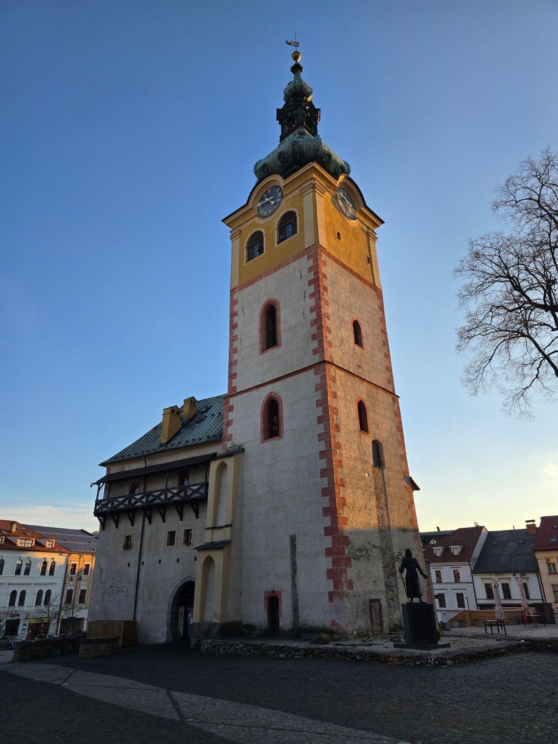 Clocktower at sunset surrounded by colorful buildings. 