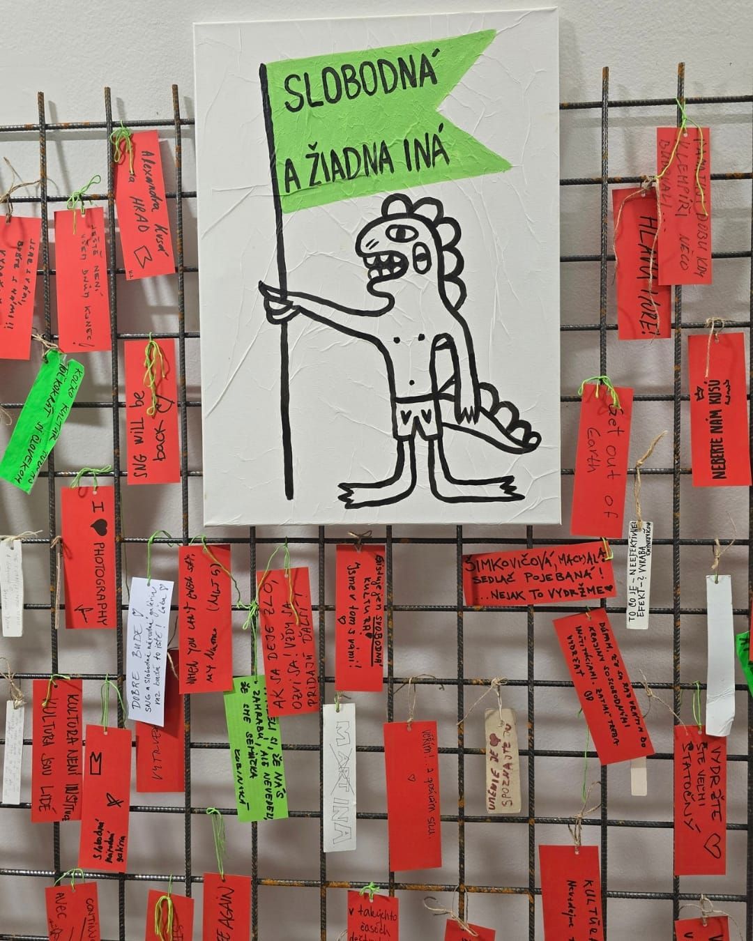 Red and some white and green paper labels bearing different messages. Large picture of dragon beneath green flag with message. 