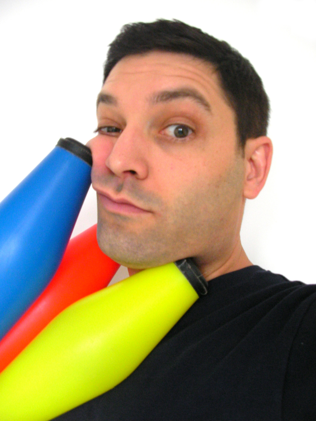 Louie Christie with juggling clubs squashed against his face