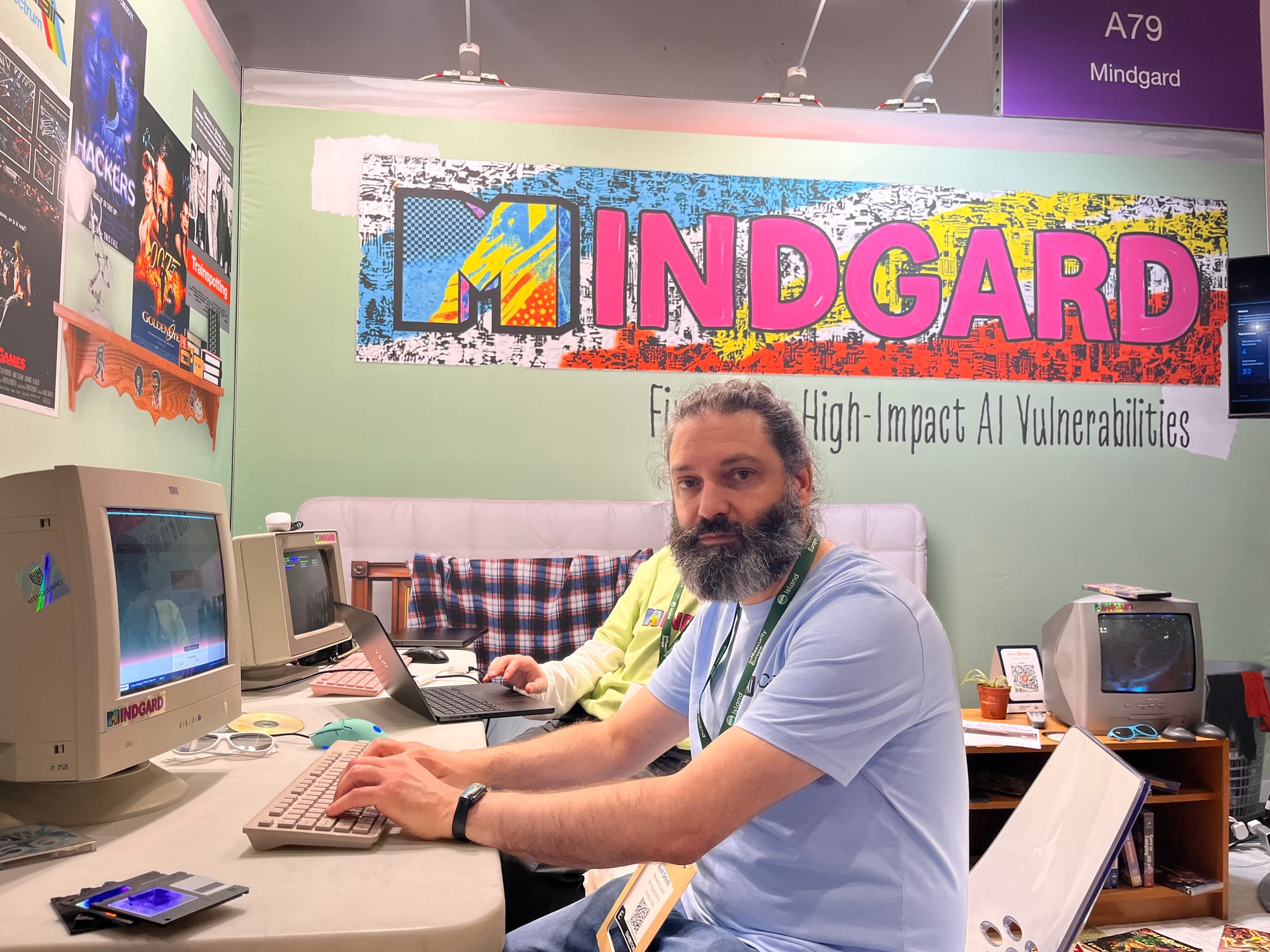 Louie sat at a 90s computer with cathode ray tube monitor, a luminous sign in the background says ‘Mindgard’