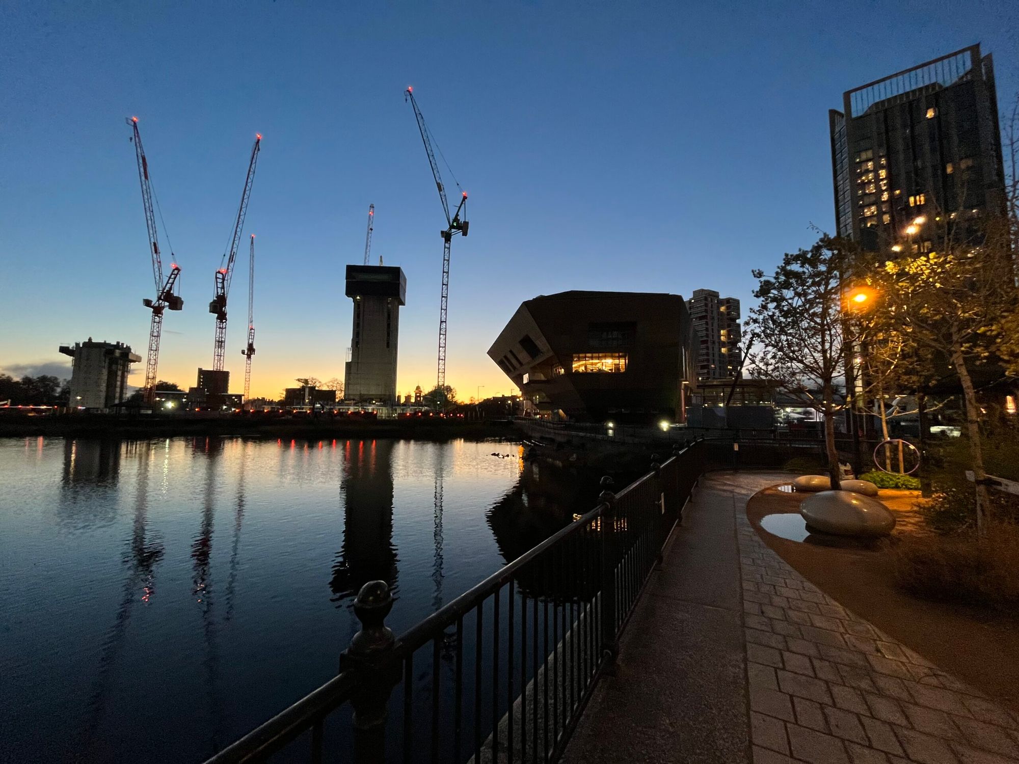 City sunset 🌆over a lake with an hexagonalo/angular/polygon shaped building next to it that looks like the Star Wars sand cr
