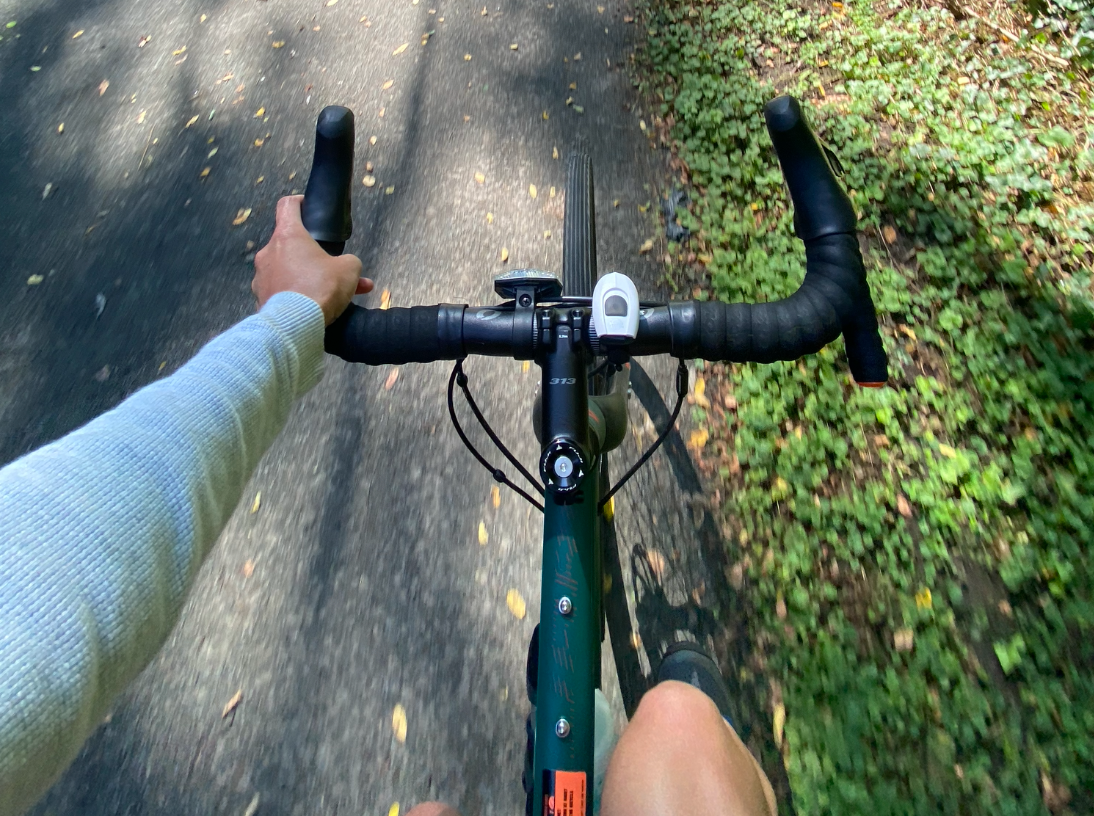 Beal rides her teal-and-orange bike one-handed on the bike path.