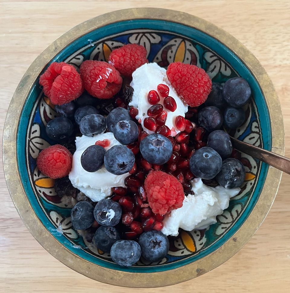 A pretty morrocan bowl full of porridge, flaxseed, sunflower and poppy seeds, blueberries, raspberries, pomegranate seeds and greek youghurt