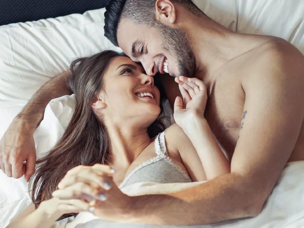 Couple lying in bed smiling and looking at each other affectionately.