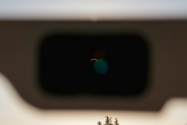 A crescent sun viewed through a dark protective solar eclipse filter.