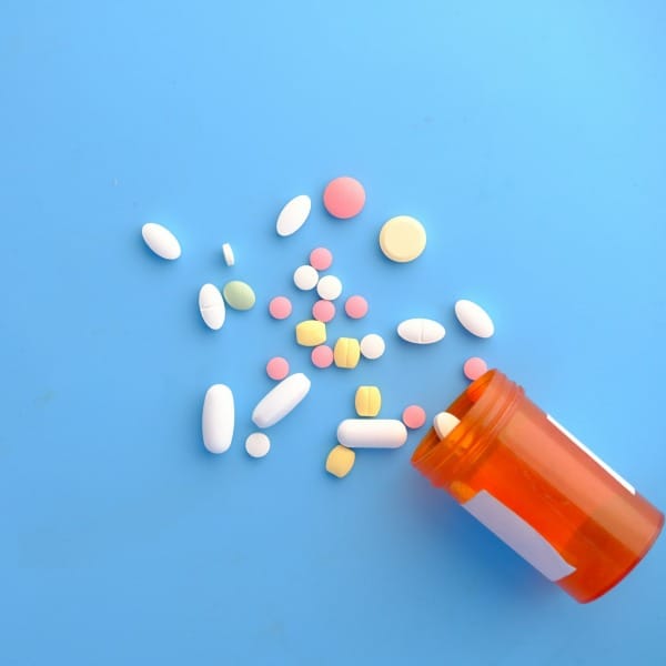 colorful pills spilling from orange bottle