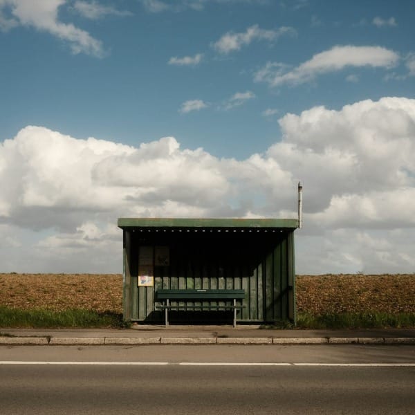 gray and white wooden house near road under white clouds and blue sky during daytime