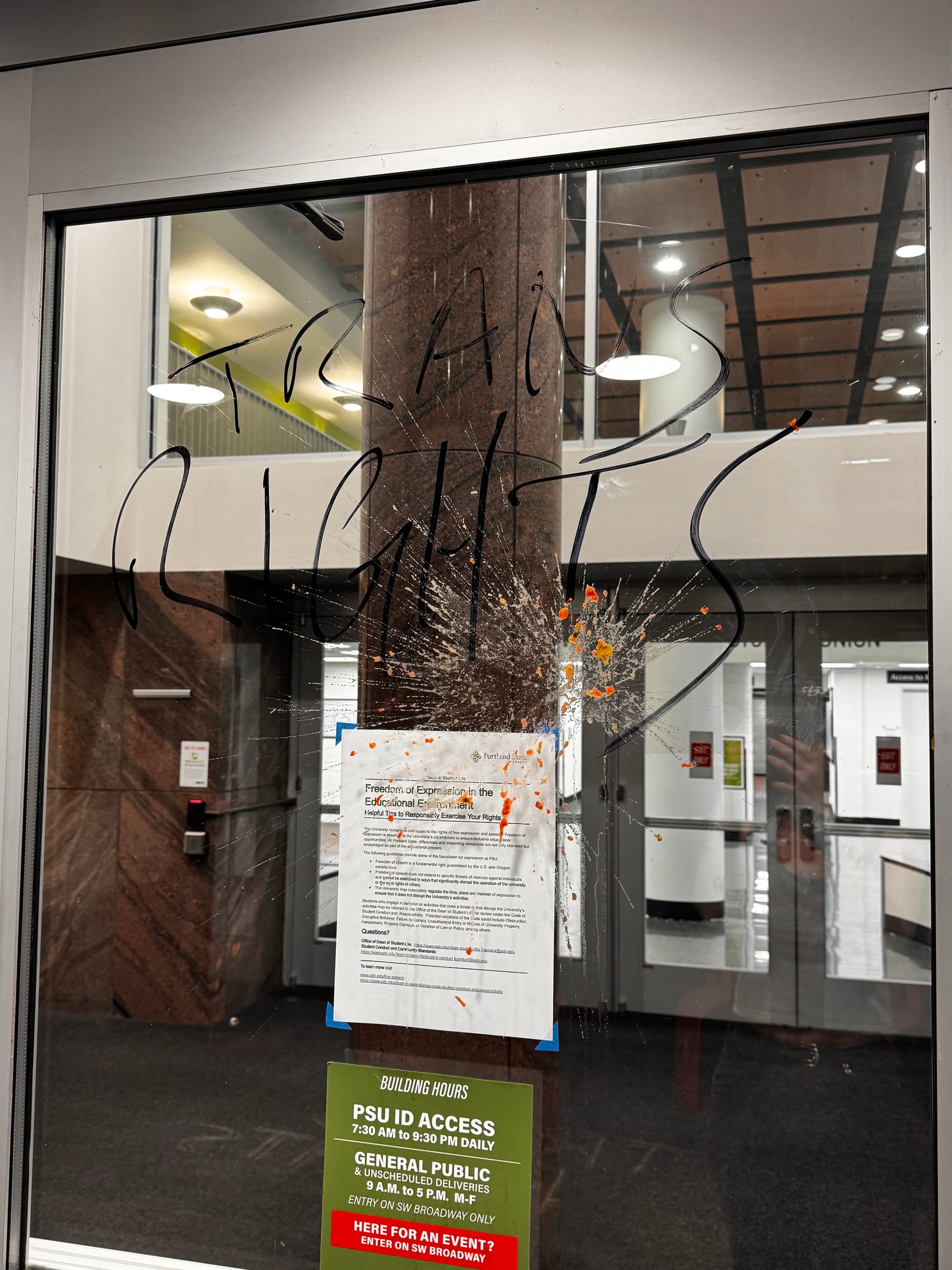 Glass door entrance to Smith with Sharpie writing and orange splatter on it