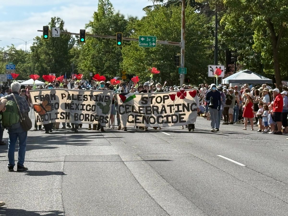 Protesters marching at Ashland 4th of July parade with banners that say “Stop Celebrating Genocide!” and “From Palestine to Mexico, Abolish Borders"