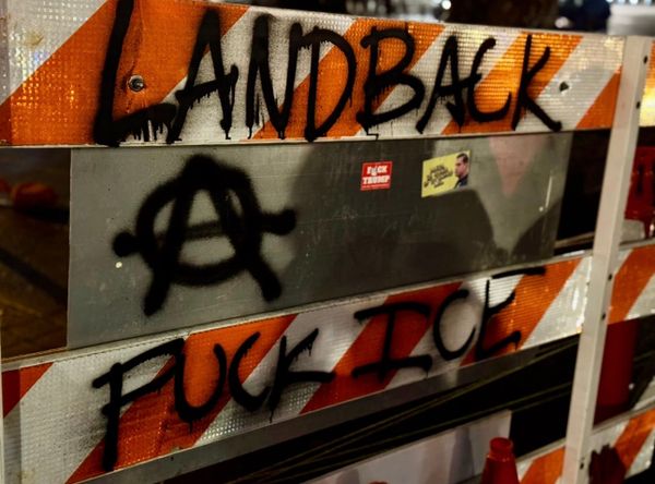 Barricade at the permanent vigil, says “land back” and “fuck ICE” with a circle A 