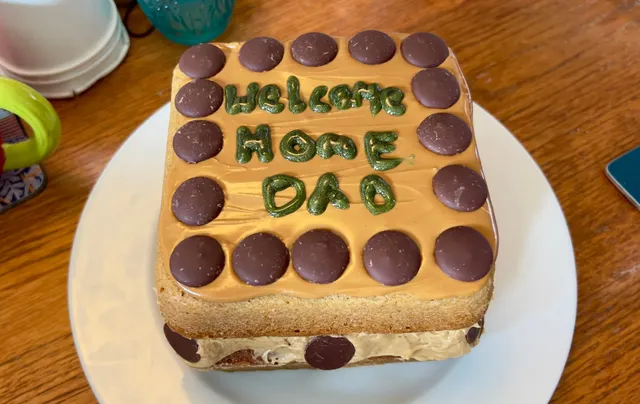 A cake with "Welcome Home Dad" in icing on the top