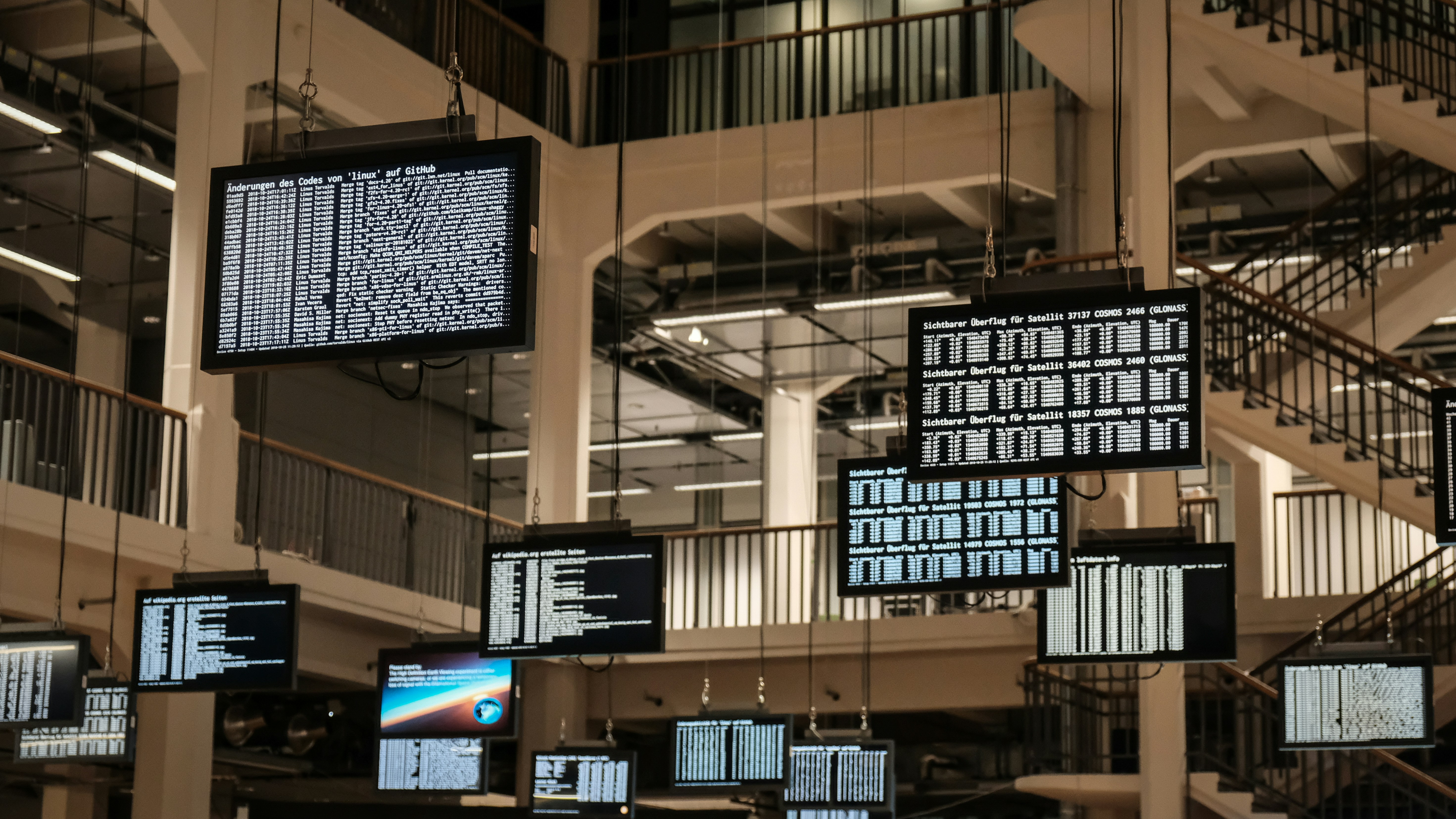Screens hanging from ceiling with various types of data.