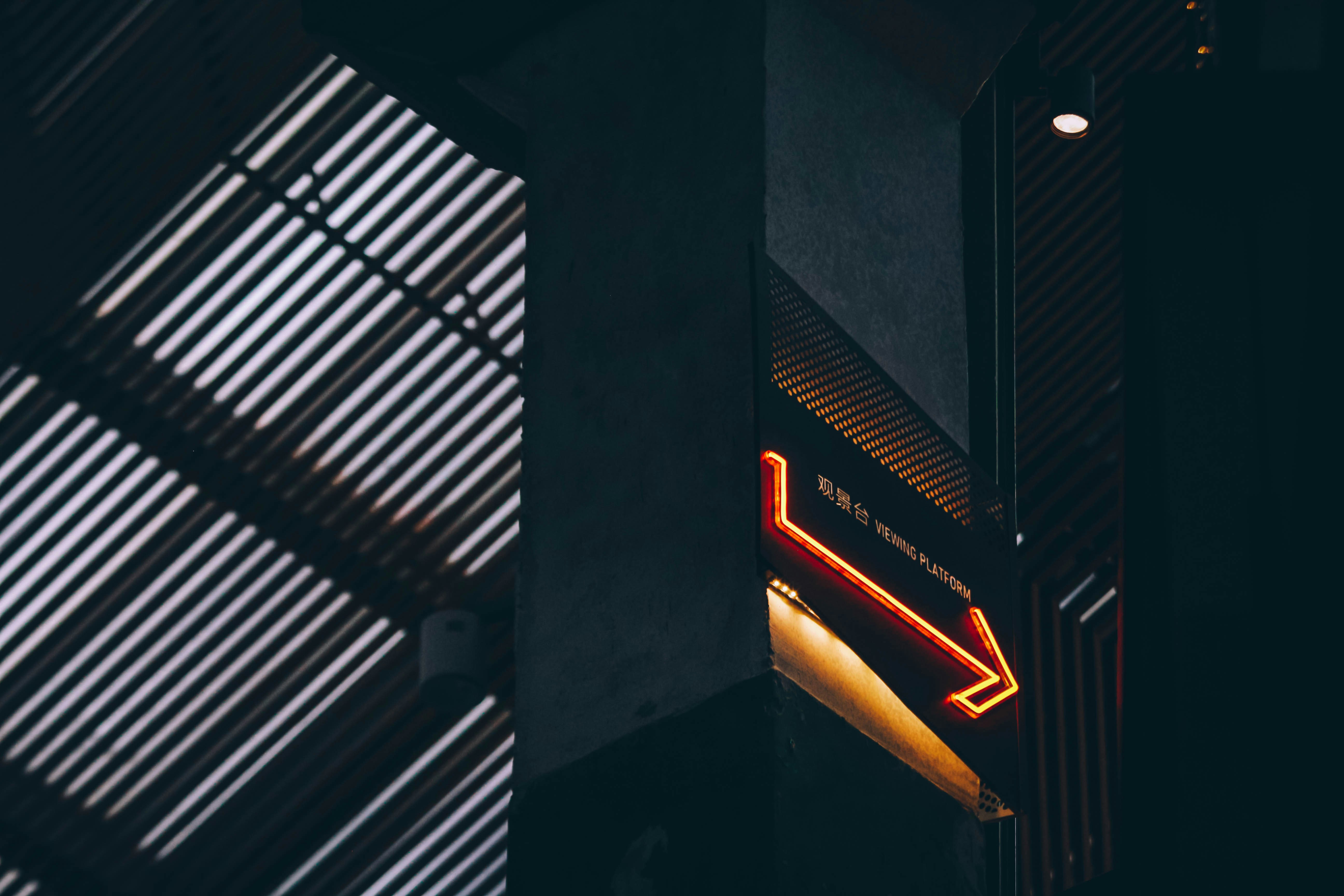 Grid lines going in one direction with neon arrow pointing in opposite direction.