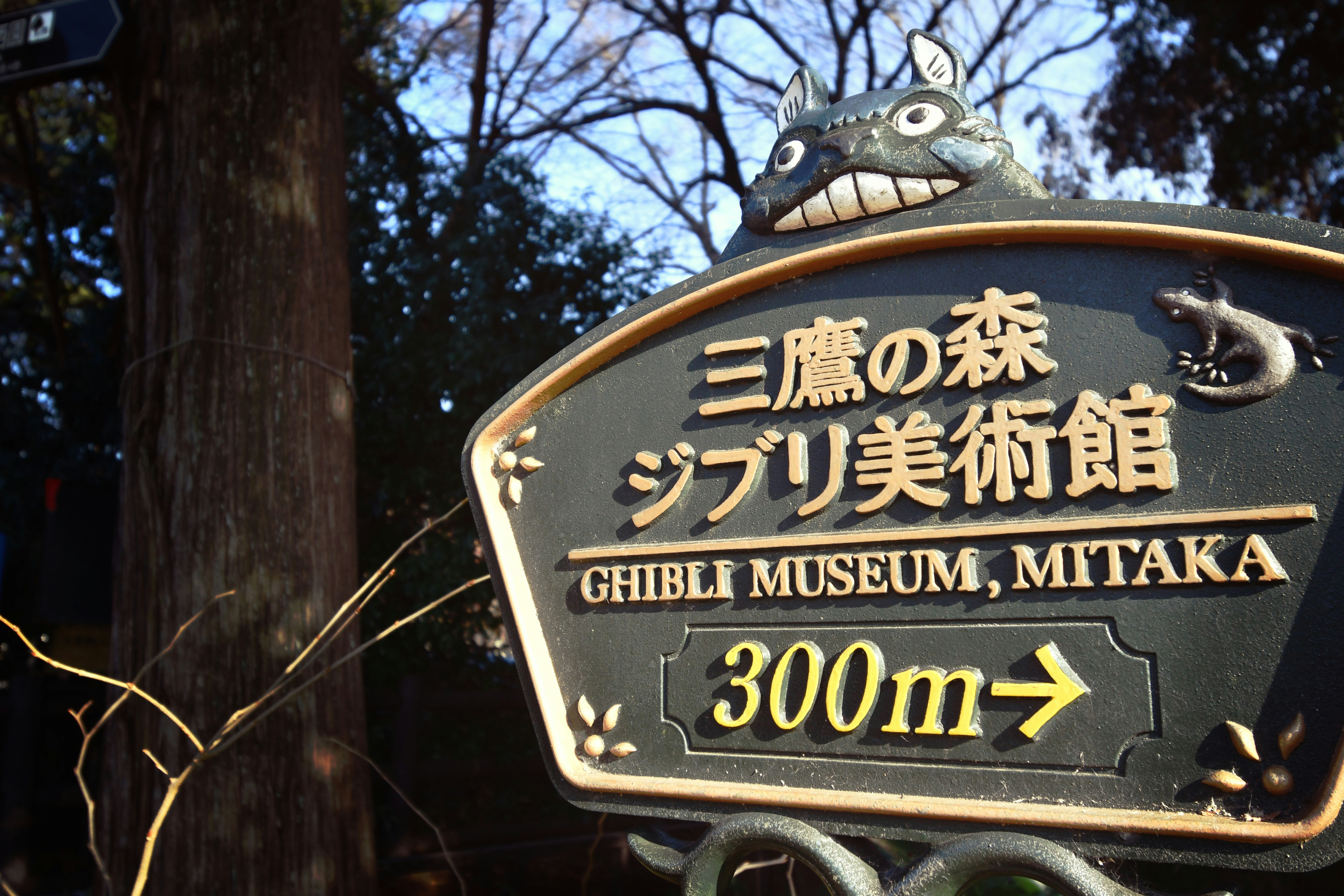 Black sign with black lettering in English and Japanese pointing to the Ghbili Museum.