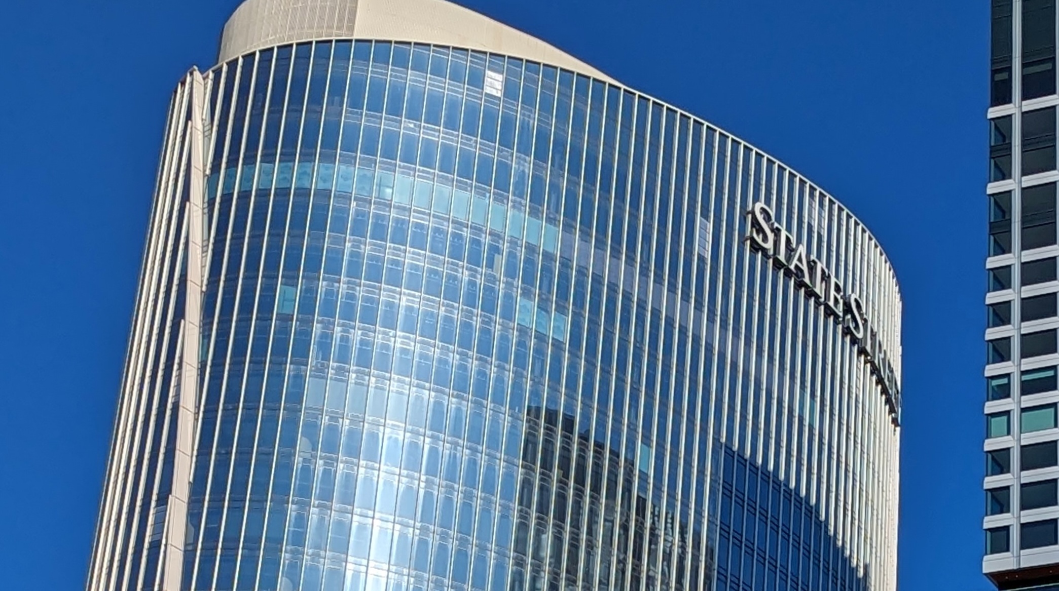 Glass high-rise office tower with the “State Street” logo on the upper floors, located at One Congress in Boston, against a clear blue sky.