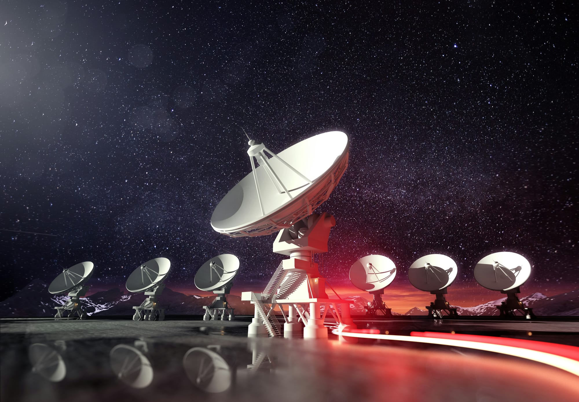 Array of large radio telescope dishes pointed toward the night sky under a field of stars.