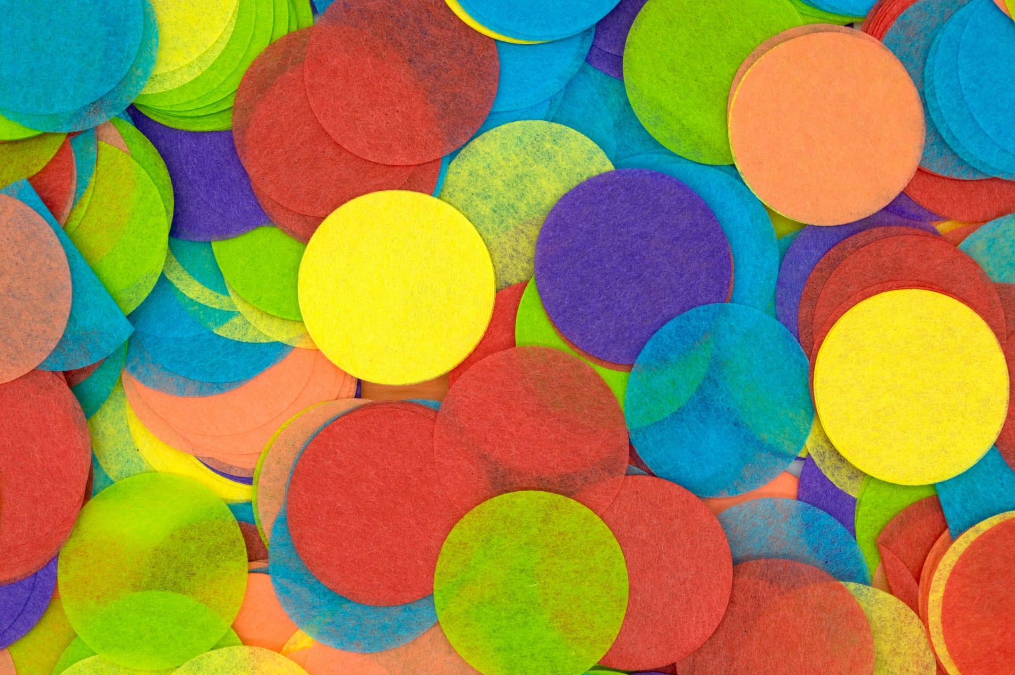 Colorful overlapping paper circles in bright yellow, green, blue, red and purple scattered across the frame.