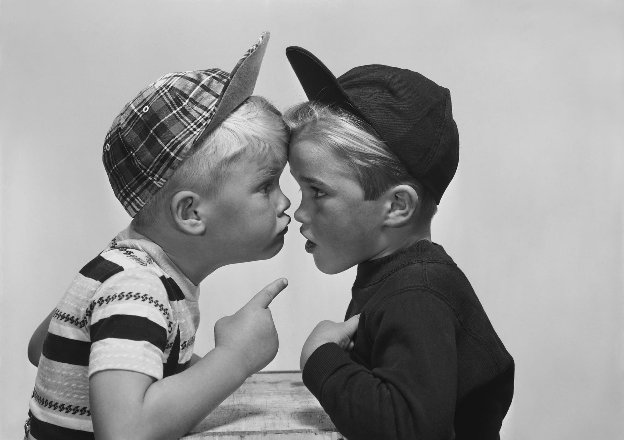 Two boys argue nose-to-nose in a vintage black-and-white photo.